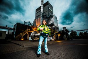 vrouwelijke werknemer staat geposeerd voor afvalverwerkingsfabriek