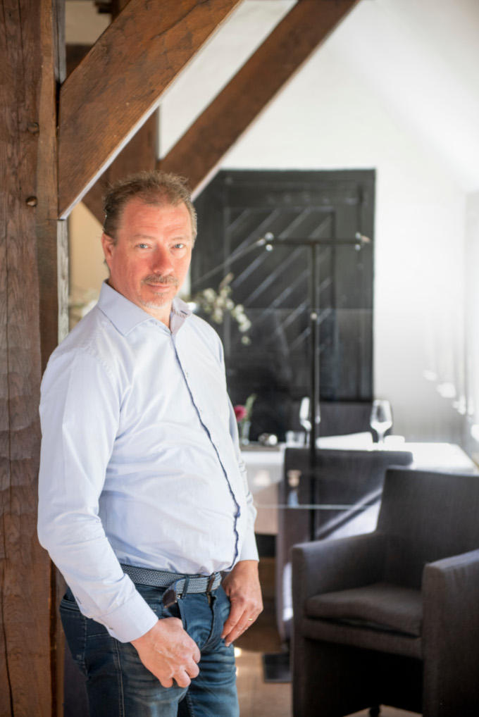 Hij is klaar voor heropening, zegt restauranthouder Arno Huisken. Achter hem is nog net de plexiglas plaat te zien. Die heeft hij geplaatst om gasten veilig te kunnen laten dineren. 