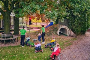 Kinderen en begeleiders van kinderopvang de Maashoeve wachten voor een meegebracht stoplicht, als symbool voor de stilstand in de kinderopvang