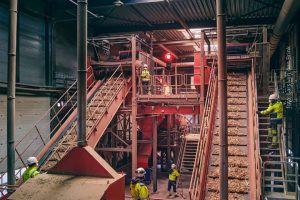 Medewerkers van afvalverwerker Renewi lijken te stoppen met werken door het rode stoplicht dat midden in de fabriekshal staat. Het is symbool voor de obstakels die de industrie hinderen om te verduurzamen en te groeien.