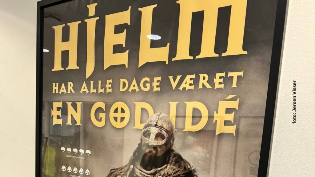 Deense campagneposter die fietsers aanmoedigt een helm te dragen, als voorbeeld van gedragssturing via voorlichting in plaats van verplichting.