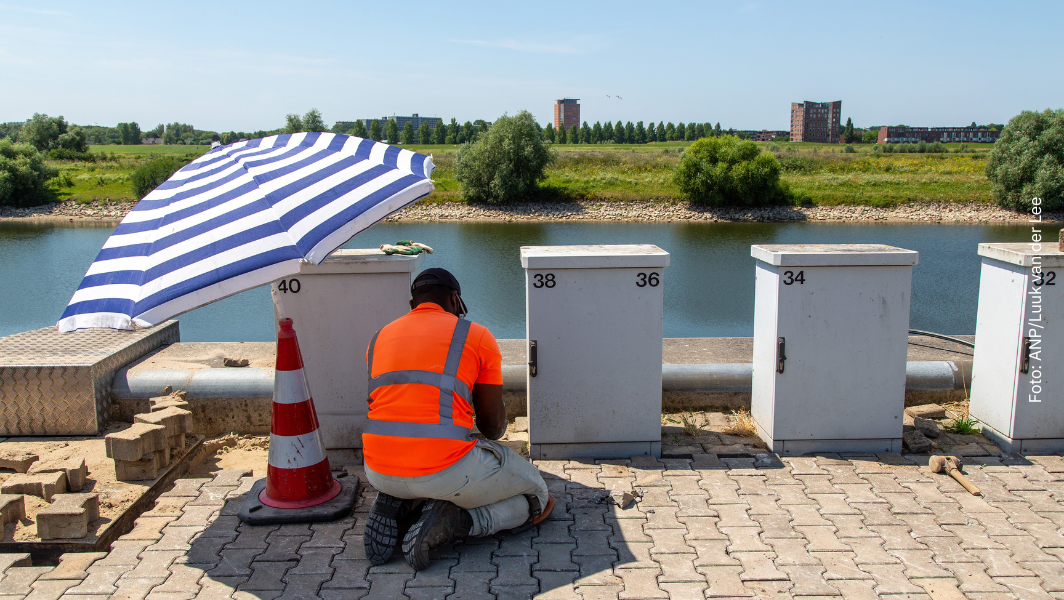 Nederland. Arnhem. 13-07-2026. Een stratenmaker is aan het werk onder een parasol. LUUK VAN DER LEE / ANP
